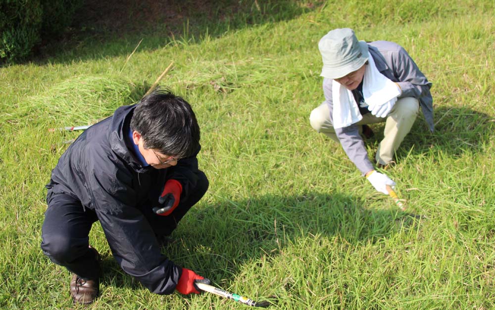 草刈りをする長友学長（右）と加藤久雄副学長